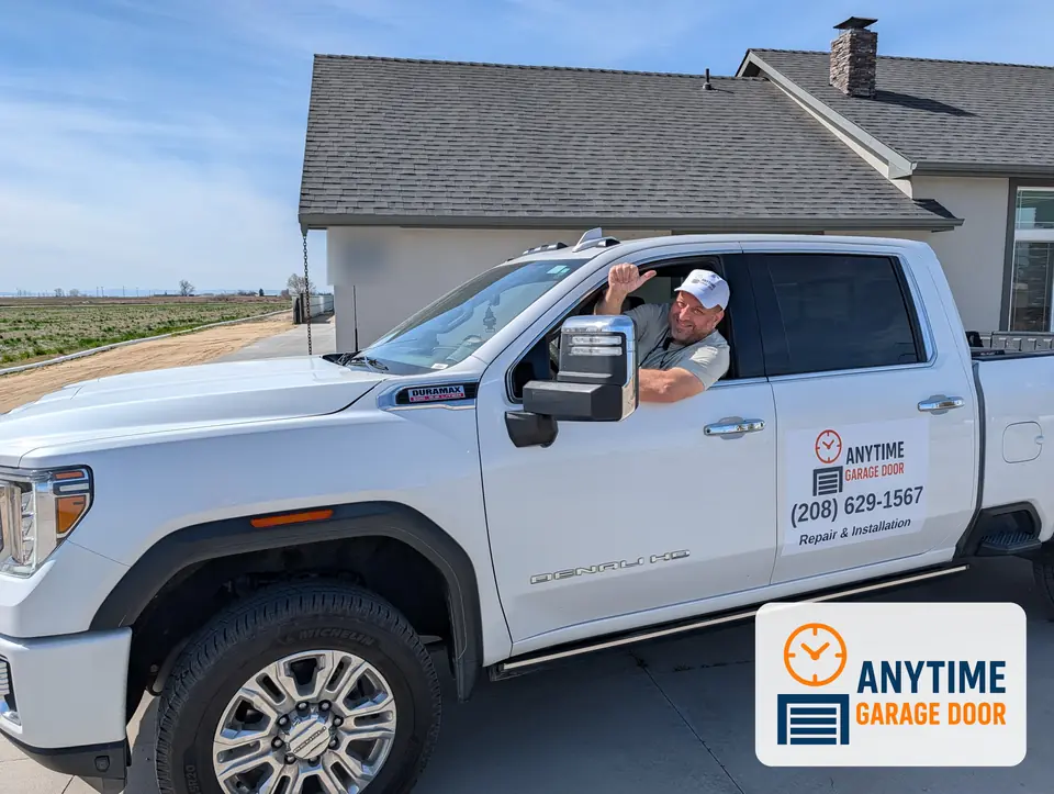 Man in an Anytime Garage Door cap leaning out the window of a white pickup with the company logo on the door
